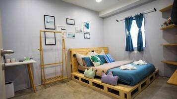A bedroom with a bed, a desk, a wardrobe, and a window with curtains.