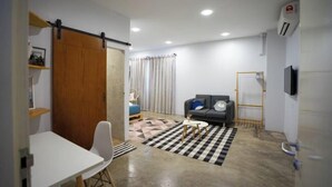 A compact living space with a sofa, a dining table, and a TV. - Buddy Station (Semporna)