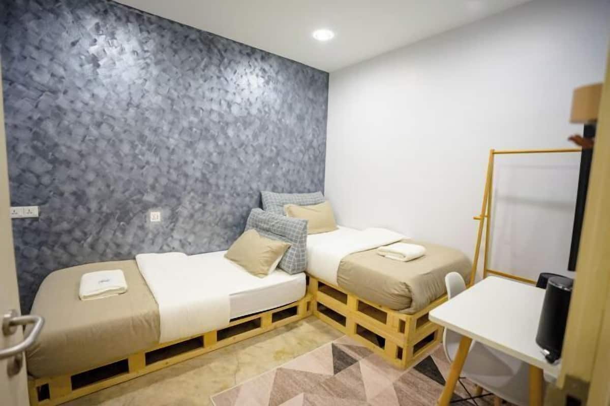 A small room with two beds, a desk, and a whiteboard.