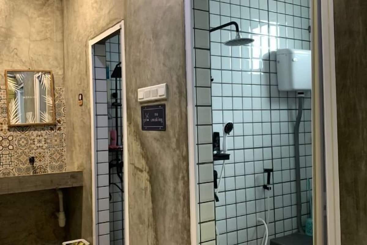 A bathroom with a shower, a towel rack, a mirror, and a tiled wall.