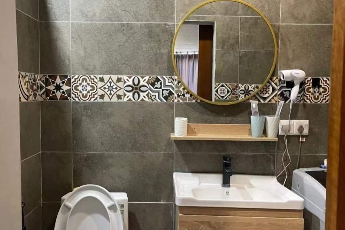 A bathroom with a toilet, sink, and mirror.