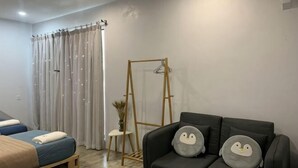 A room with a bed, a sofa with decorative pillows, a wooden ladder, and a curtain. - Buddy Station (Semporna)