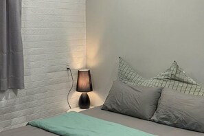 Een slaapkamer met een bed, een lamp en een muur met een bakstenen patroon.