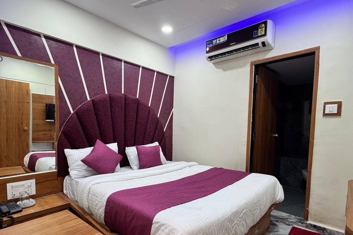 Ein modernes Schlafzimmer mit einem großen Bett, einem Holfnachtkästchen, einem Spiegel und einem Deckenventilator.
