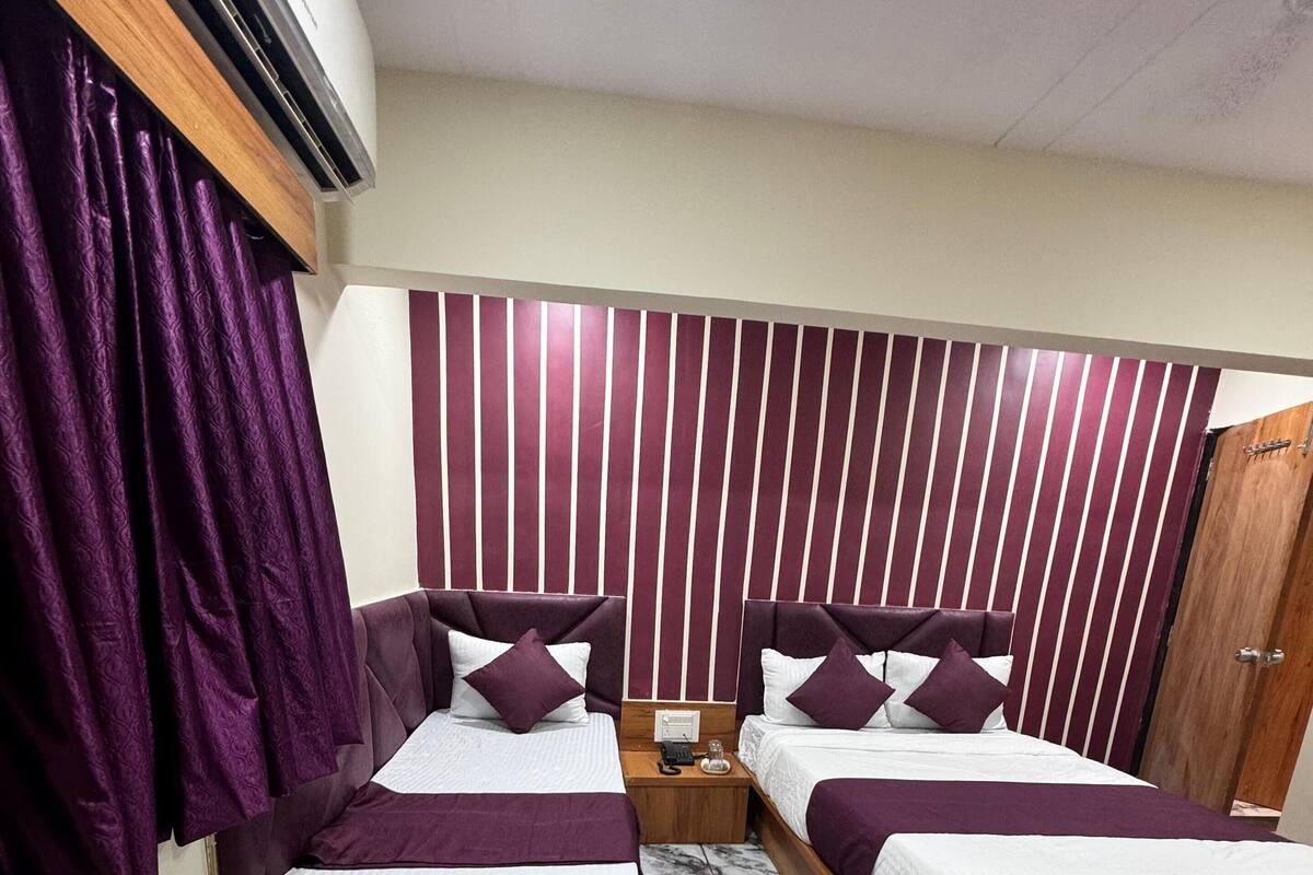 Ein Hotelzimmer mit zwei Betten, einem hölzernen Kopfteil, einem Marmorboden und einer Wand mit vertikalen Streifen.