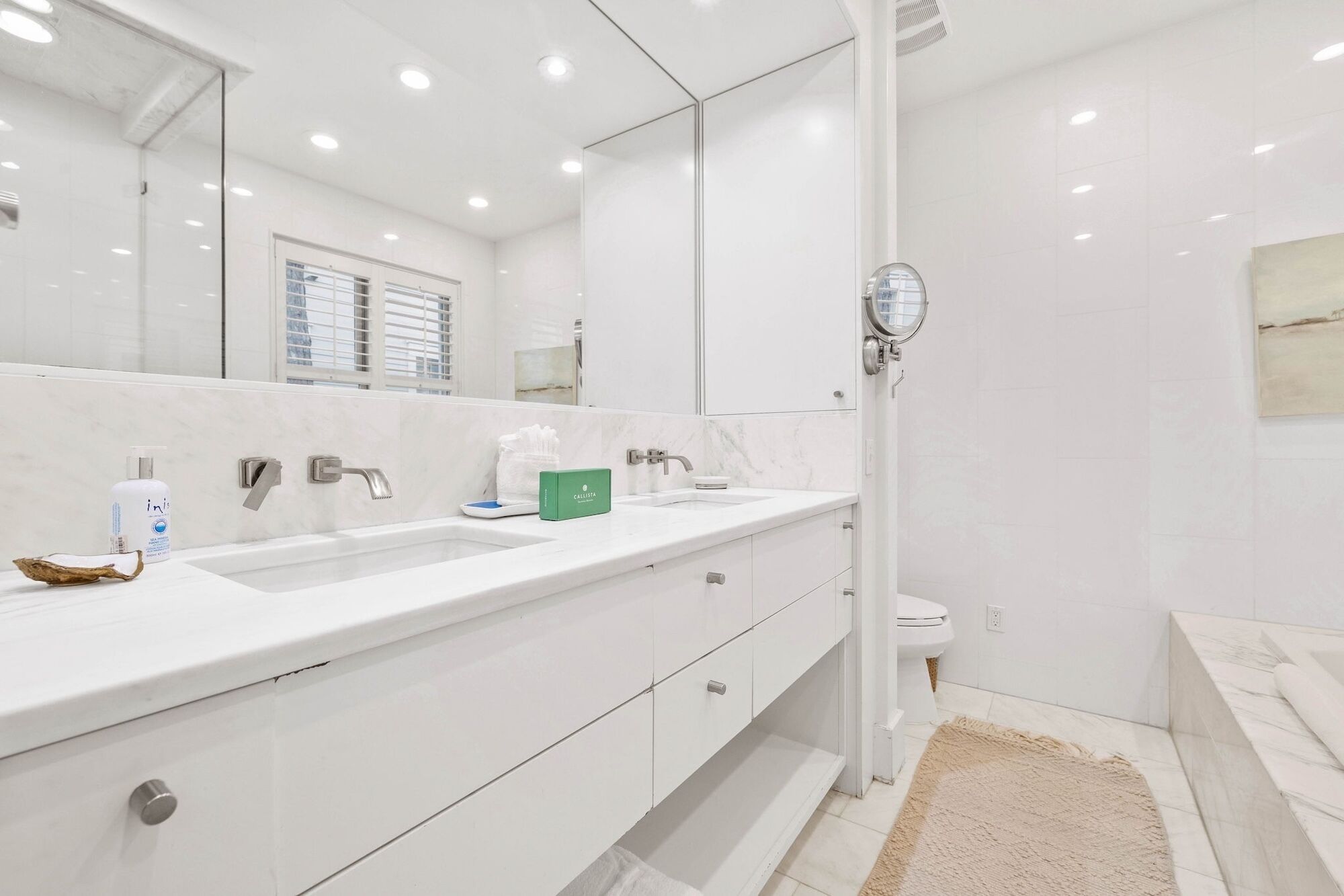 Un bagno moderno con un mobile lavabo bianco, due lavandini, uno specchio grande e uno spazio doccia.