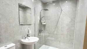 A modern bathroom with a toilet, sink, and walk-in shower. - Cozy Newcastle Apartment With 2 Bedrooms (Newcastle-upon-Tyne)