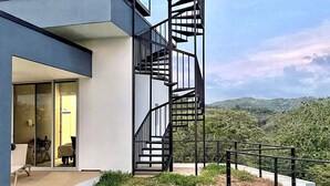 A modern house with a unique spiral staircase, a glass door entrance, and a view of the surrounding landscape.