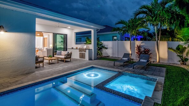A modern outdoor pool area with a hot tub, lounge chairs, and a barbecue grill. - Coastal Luxury Home with Pool, Spa & Gourmet Kitchen (Naples)
