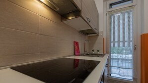A modern kitchen with a black induction cooktop, a stainless steel range hood, and a window with a view of the outdoors. - A Casa di Ines by Wonderful Italy (Turin)