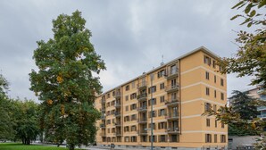 A multi-story yellow building with balconies, surrounded by greenery and a grassy area. - A Casa di Ines by Wonderful Italy (Turin)