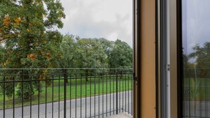 A balcony with a metal railing overlooking a road and a grassy area with trees. - A Casa di Ines by Wonderful Italy (Turin)
