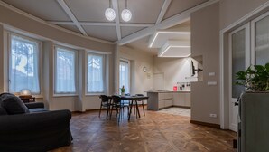 Zona d'estar àmplia amb taula de dinar, sofà i cuina al fons.
