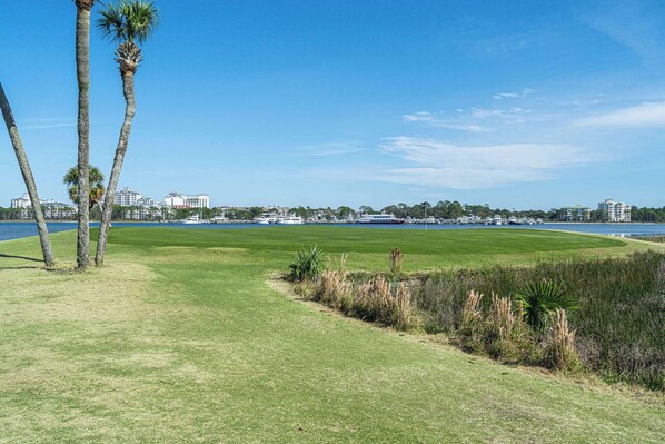 A golf course with a clear view of the water and buildings in the background.