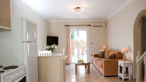 A compact kitchen with a stove, a refrigerator, and a dining area with a table and chairs. - Stunning 2-bed House in Lefkas (Lefkada)