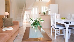 A modern living room with a glass coffee table, a sofa, and a dining area with white furniture. - Stunning 2-bed House in Lefkas (Lefkada)