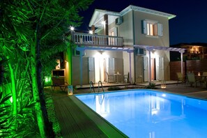Una casa de dos pisos con piscina, mobiliario exterior y balcón.