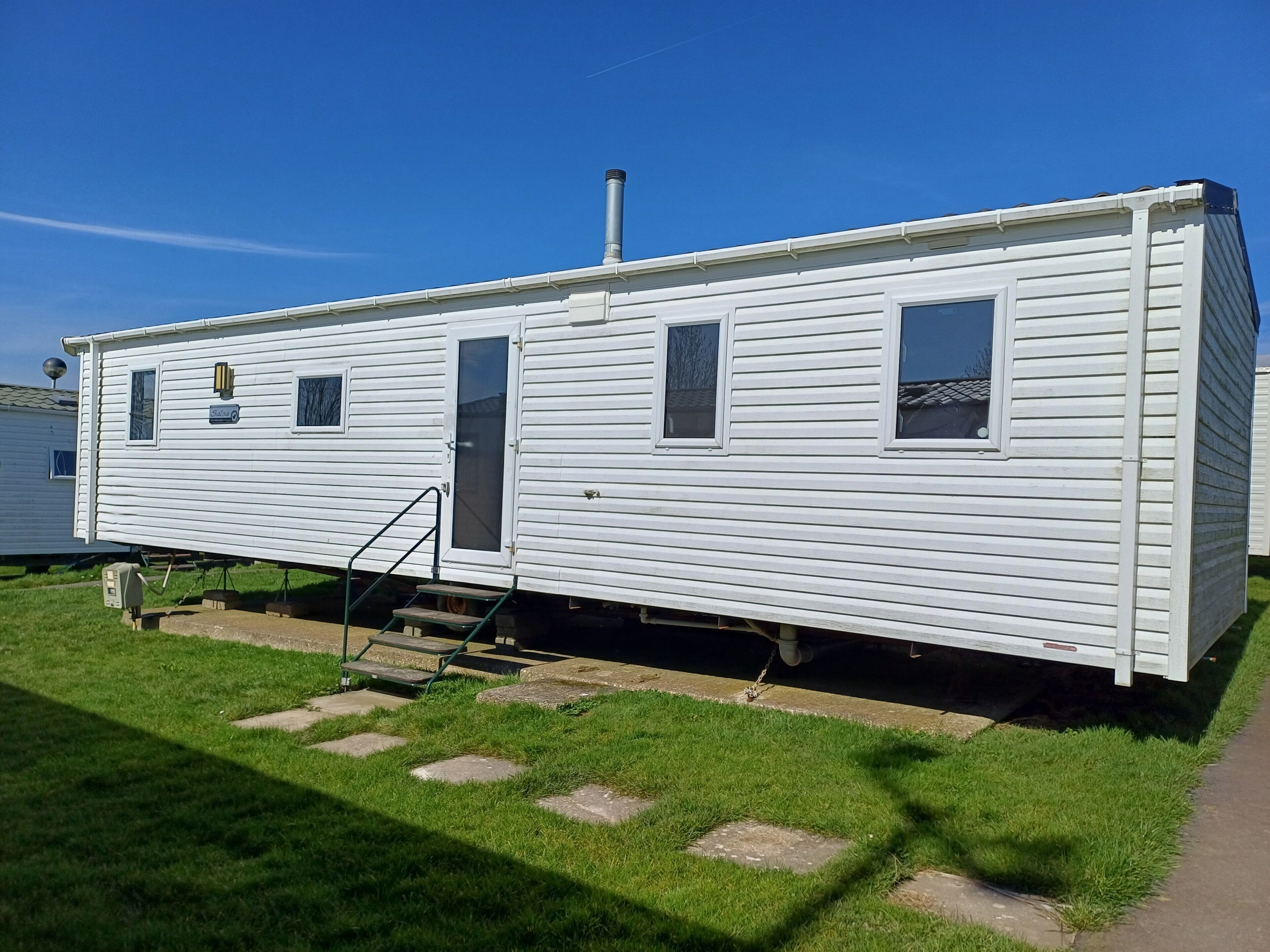 A white mobile home with a small porch and a sliding door.
