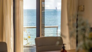 Quarto com vista para o mar através de uma janela com cortinas.
