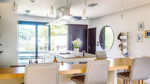 Uma cozinha moderna com ilha de madeira, banquetas, iluminação pendente e uma janela grande com vista para o exterior.