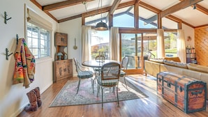 A dining area with a wooden table and chairs, a large window, and a view of the outdoors. - Cozy Mtn-View Chalet < 2 Mi to Windham Slopes (Windham)