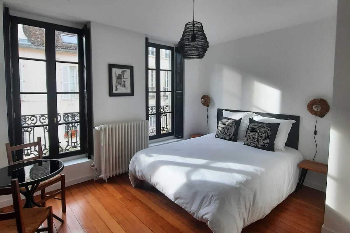 A bedroom with a large bed, a dining table, and chairs.