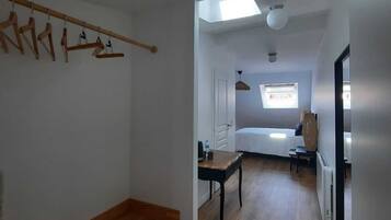 A room with a wooden bench, a skylight, a bed, and a radiator.