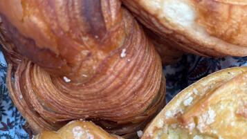 Variedad de pasteles, incluyendo croissants y hojaldres, sobre un tejido estampado.