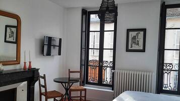 Een slaapkamer met een bed, een bureau met stoel, een televisie en een raam met uitzicht.