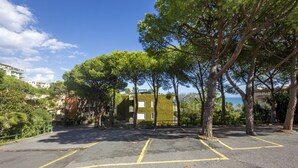 A parking area with trees and a building in the background. - La Pineta sul Mare by Wonderful Italy (Sanremo)