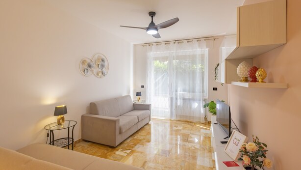 A modern living room with a sofa, a coffee table, a TV, and a ceiling fan. - La Pineta sul Mare by Wonderful Italy (Sanremo)