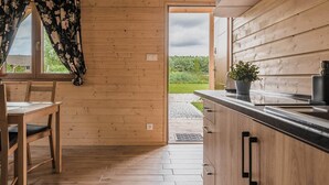 A wooden interior with a dining table, chairs, a kitchen counter, and a view of the outdoors.