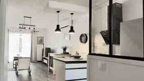 A modern kitchen with white cabinetry, a central island, pendant lighting, and a view into the dining area.
