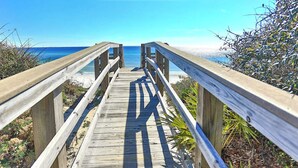 A wooden boardwalk leading to a beach with clear skies.