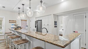 A kitchen with a granite countertop, white cabinetry, and a stainless steel refrigerator.