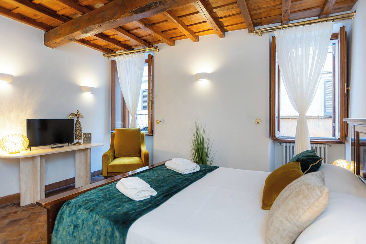A hotel room with a bed, a television, a chair, and a window with curtains.