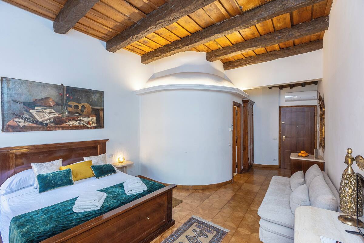 A bedroom with a wooden bed, a nightstand, a wall-mounted lamp, and a painting.