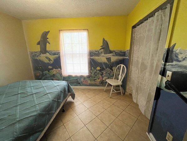 Une pièce comprenant un lit, une chaise, une fenêtre et une fresque murale.