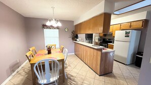 A compact kitchen with a dining area, wooden cabinets, and a built-in island. - Sleeps 10•Near HWY I-95,40,17 & Kings Bay navybase,Cumberland Island,JAX airport (Kingsland)