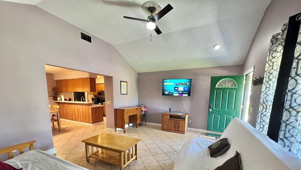 A living room with a sofa, a coffee table, a TV, a green door, and a kitchen in the background. - Sleeps 10•Near HWY I-95,40,17 & Kings Bay navybase,Cumberland Island,JAX airport (Kingsland)