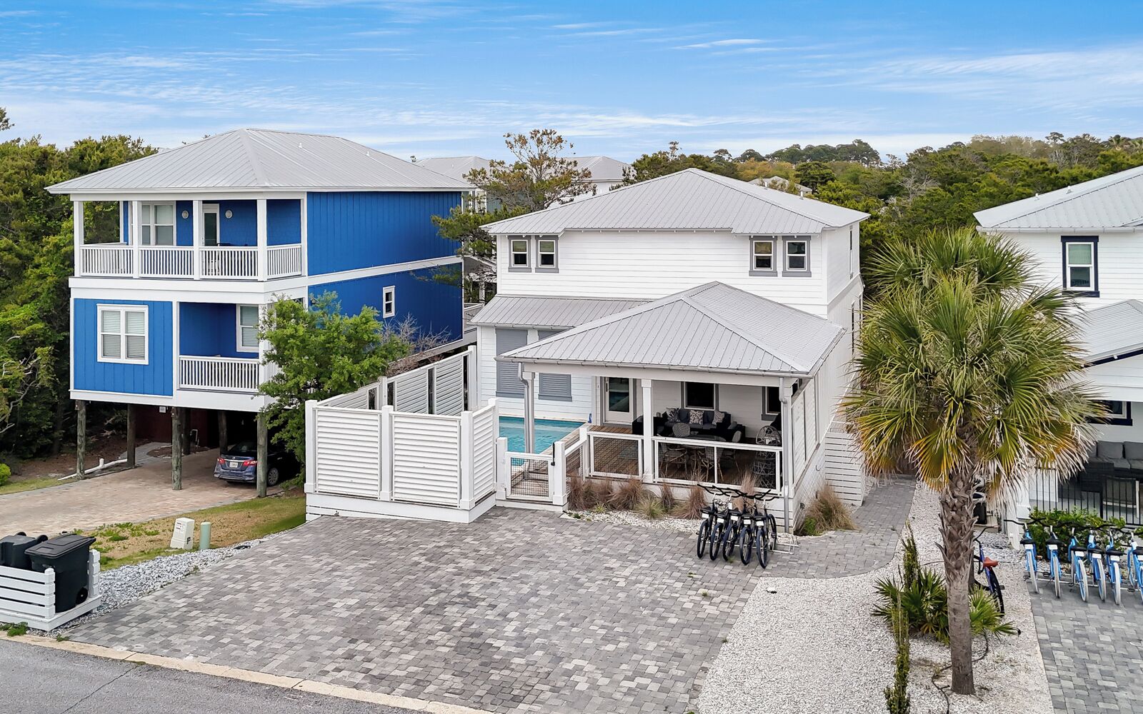 A beachfront property with a two-story blue house, a white house with a balcony, and a small pool area.