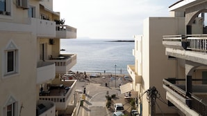 A coastal view from a balcony overlooking a beach with buildings and a clear sky. - Niman Beachside Apartments (Chania)