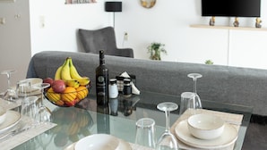 A dining table set with plates, glasses, a bowl of fruit, and condiments. - Niman Beachside Apartments (Chania)