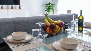 A dining table set with bowls, wine glasses, and a fruit bowl containing bananas, apples, and oranges. - Niman Beachside Apartments (Chania)