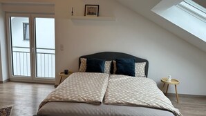 Una camera da letto con un letto, un comodino, una finestra e una porta che dà su un balcone.