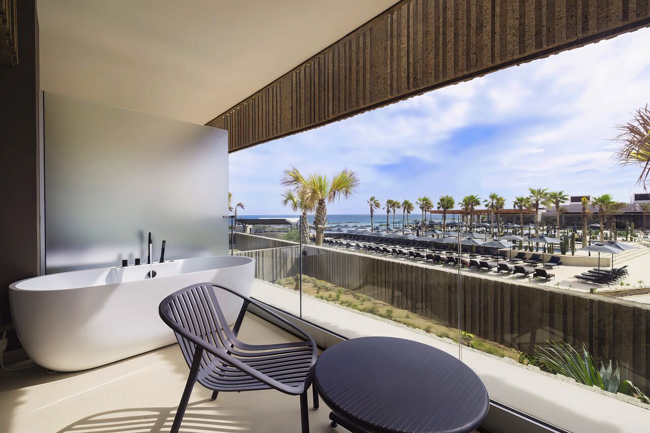 A balcony with a bathtub, a chair, and a table.