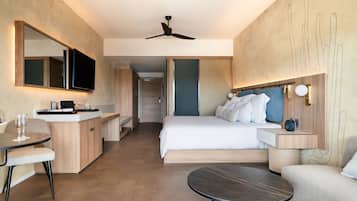 A modern hotel room with a bed, a desk, a chair, a round table, and a ceiling fan.