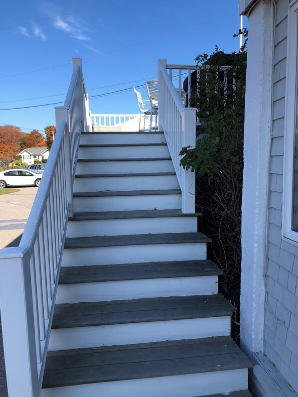 A set of white wooden stairs with a white railing, leading up to a porch area.