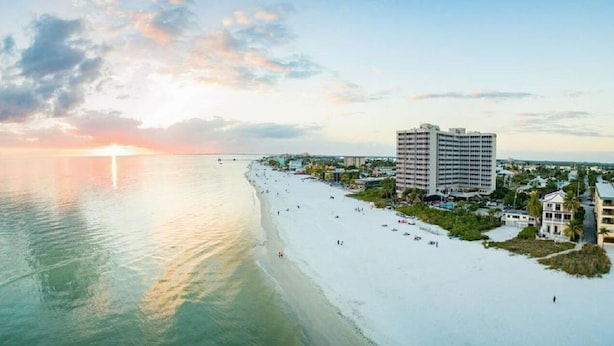 A beachfront hotel with a large building, a sandy beach, and a sunset. - Ocean/Pool View 703- Relax and recharge at Fort Myers Beach (Fort Myers Beach)