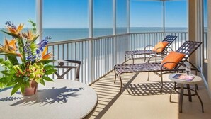 A balcony with a view of the sea, featuring a round table, two chairs, and a potted plant. - Ocean/Pool View 703- Relax and recharge at Fort Myers Beach (Fort Myers Beach)